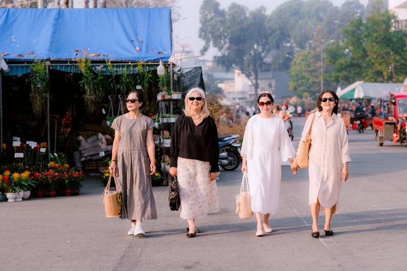 Senior women enjoying a sunny day at an outdoor market, showcasing modern style and confidence.